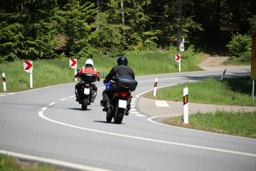 Gruppe von Motorradfahrern auf einer kurvenreichen Landstraße
