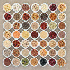 Vegan high protein dried health food collection with nuts, seeds, legumes, pasta, grains and cereals. Foods high in fibre, antioxidants, anthocyanins, vitamins and minerals. Top view on hessian.