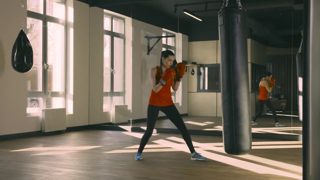 Wide shot of young woman training punching bag. Slow motion