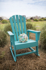 Bridal bouquet with sea shells on adirondack chair.