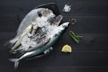 Papier Peint photo autocollant Poisson Fresh fish with ice in ceramic tray on dark wooden background. Flat lay. Top view