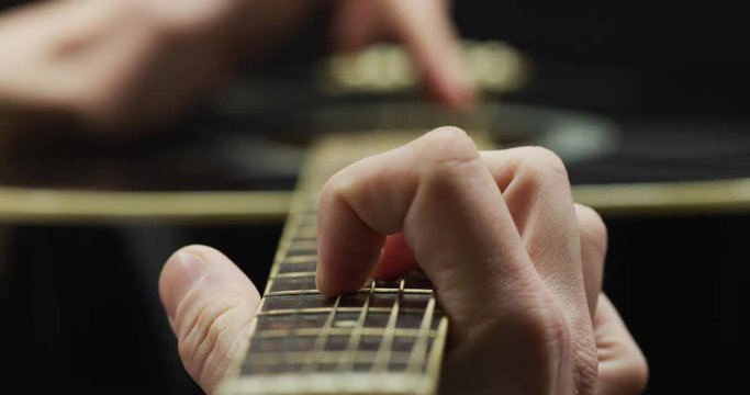 Fingers playing on the fretboard of a guitar