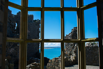 view over window of old medieval castle on ocean in northern ireland