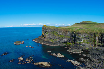view on cliffs and ocean coast of northern ireland. volcanic rock formation on edge of water. blue sky and sunny day 