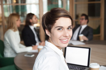 Ambitious attractive smiling young businesswoman looking at camera at group meeting, happy...