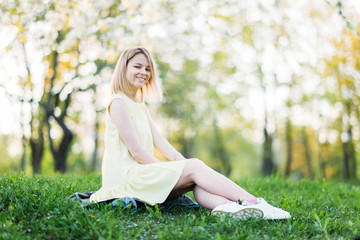 beautiful young woman in yellow dress in a blooming park posing.