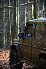 Dirty offroad car with fall forest on background
