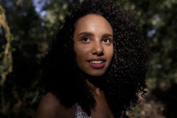 portrait outdoors of a beautiful young afro american woman smiling at sunset. Black background. Lifestyle. Nature