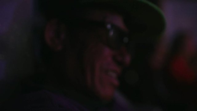 Close-up of old man in black sunglasses sitting in the dark.
