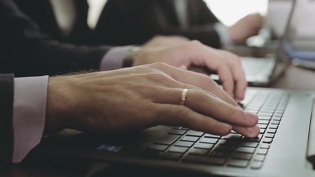 Hands of a man typing on a computer keyboard. A business meeting.