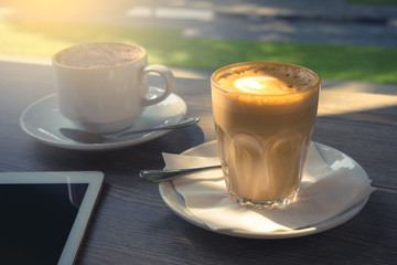 coffee and digital tablet with morning light in cafe terrace .