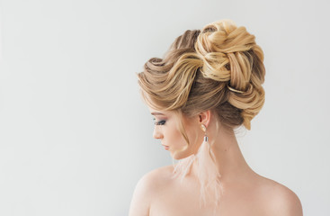 Beautiful young woman with a trendy blonde hairstyle, head and shoulders portrait on a grey studio...