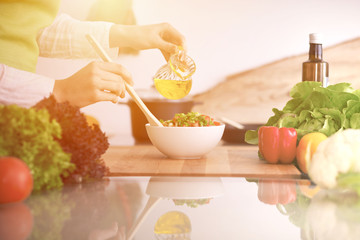Close Up of human hands cooking vegetable salad in kitchen on the glass table with reflection. Healthy meal, and vegetarian food concept