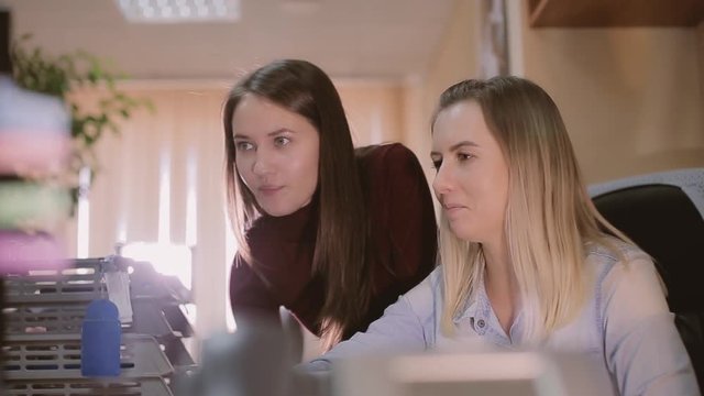 Carier start. A girl trainee in the office asks for help from a colleague.