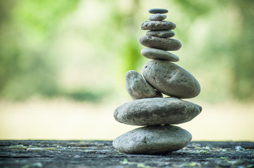 closeup of stones balance on wooden table on green blurred background