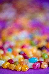 Jellybean candy on purple table receding into blurred colors.