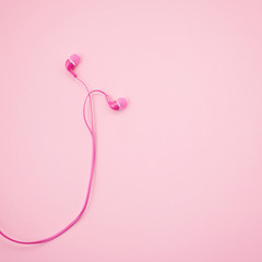 Top view of pink earphones on pink background.