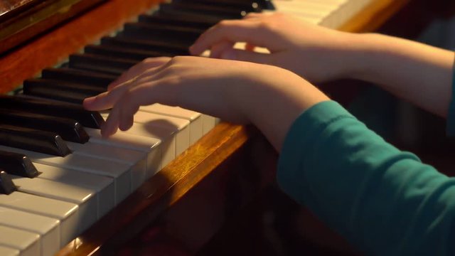 kids hands play music on a piano key
