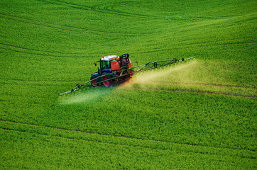 Farm machinery spraying insecticide to the green field, agricultural natural seasonal spring...