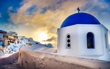 Oia town on Santorini island, Greece. Traditional and famous houses and churches with blue domes over the Caldera, Aegean sea at sunrise