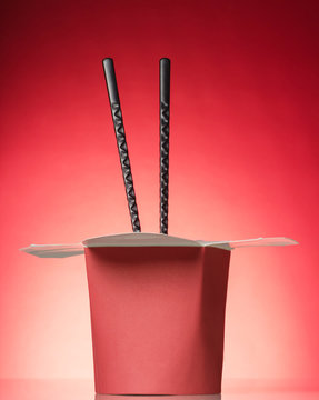 Wok box for quick hot meals and chopsticks, on red