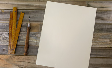 Empty distressed wood desk space with a slide rule, fountain pen, and paper, room for text and product placement 