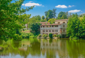Fototapeta premium Lavaur, Midi Pyrenees, France - August 4, 2017: Old French style villa on the river bank under a blue summer sky