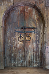 fantastic old wooden door of arch type with a bolt and two rings from old ferrous metal for design