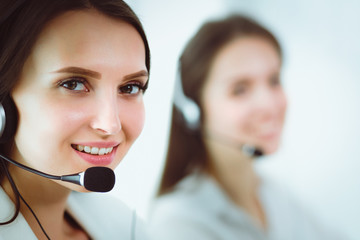 Smiling businesswoman or helpline operator with headset and computer at office