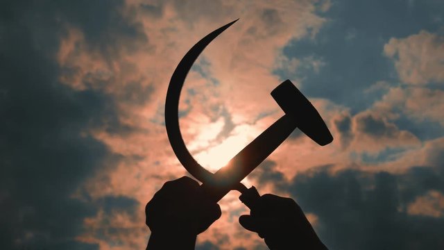 silhouette of a sickle and a hammer against the sky
