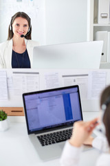 Smiling businesswoman or helpline operator with headset and computer at office