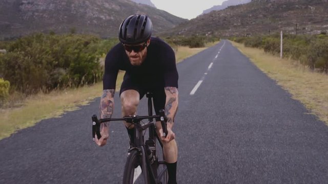 Athlete cycling on long flat road