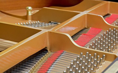Detail inside the piano with copper strings, pins and hammers