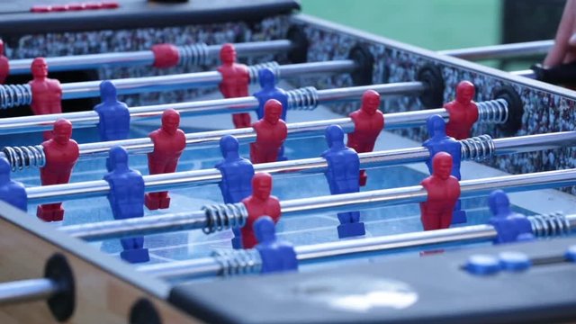 Close up, people play with foosball table