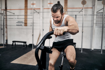 Obraz na płótnie Canvas Fit man exercising on a stationary bike at the gym