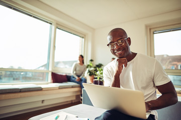Fototapeta premium Smiling African businessman working online with colleagues in th