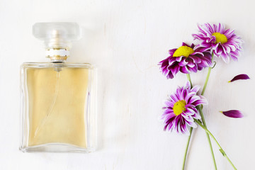 Bottle of perfume and flowers on white background