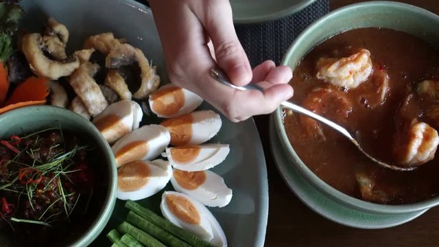 hand eating Thai traditional sour orange soup with prawn