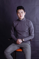 young man with casual clothes sitting on a chair with on grunge background