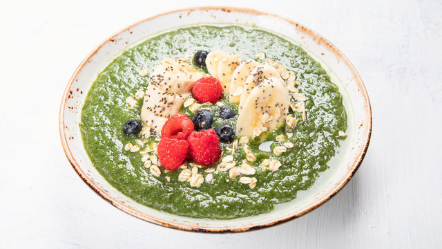 Green smoothie bowl with fresh berries for healthy vegetarian diet breakfast.