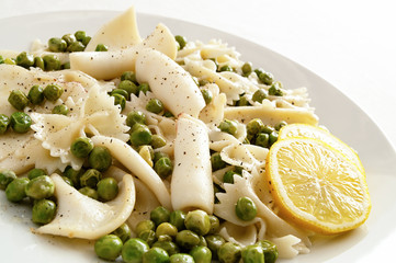 calamari with farfalle and pea decorated with lemon rings and sprinkled with black pepper