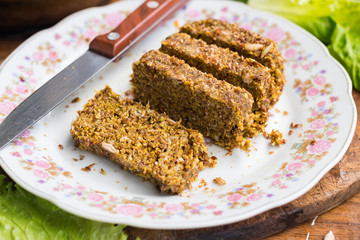 Fototapeta na wymiar Raw vegan flax bread slices with wheat sprouts and sunflower seeds. On plate served for lunch and good with fresh vegetables. Vegetarian healthy food