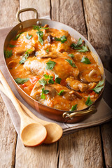 Tasty rustic French food: chicken with mushrooms stewed in sauce close-up. vertical