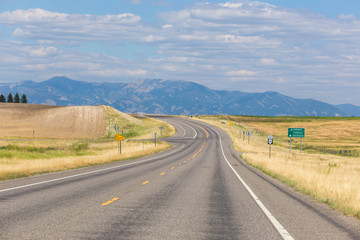 Highway curving into the distance with mountains in view.
