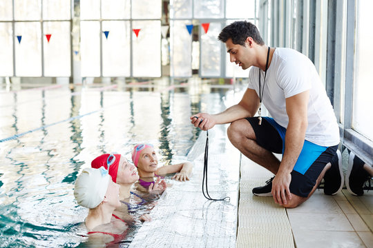 Trainer with stop-watch talking to his team in front and explaining them what they are going to do next