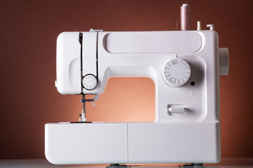 Multi-functional sewing machine, on dark red background