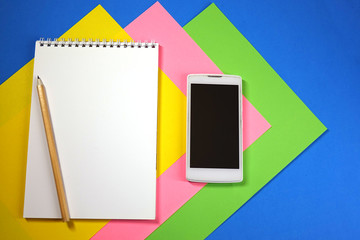 Notepad, pencil and phone on colored background top view, school, business, education