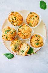 Savory potato spinach and feta muffins served on a plate. White stone background. Top view.