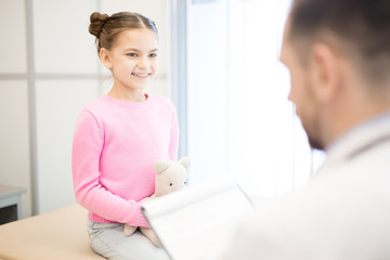 Fototapeta premium Happy little patient with toy listening to pediatrician advice about proper medical treatment