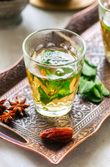 Traditional moroccan mint tea with dates on a vintage tray. White stone background.